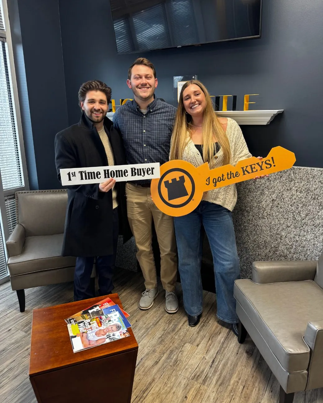 First-time home buyers holding an 'I got the keys' sign at closing